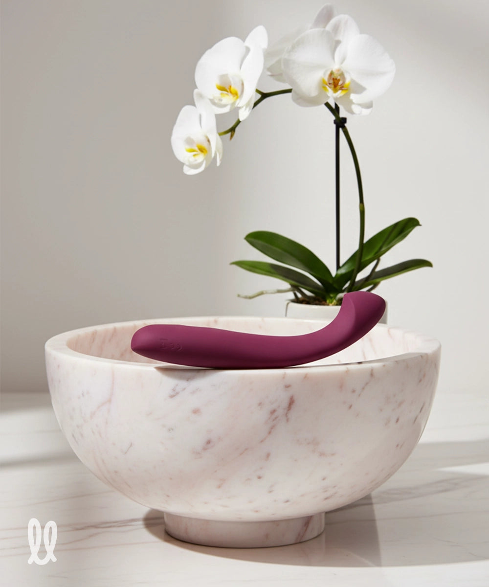 Marble bowl with purple g-spot sex toy and a white orchid in a light room