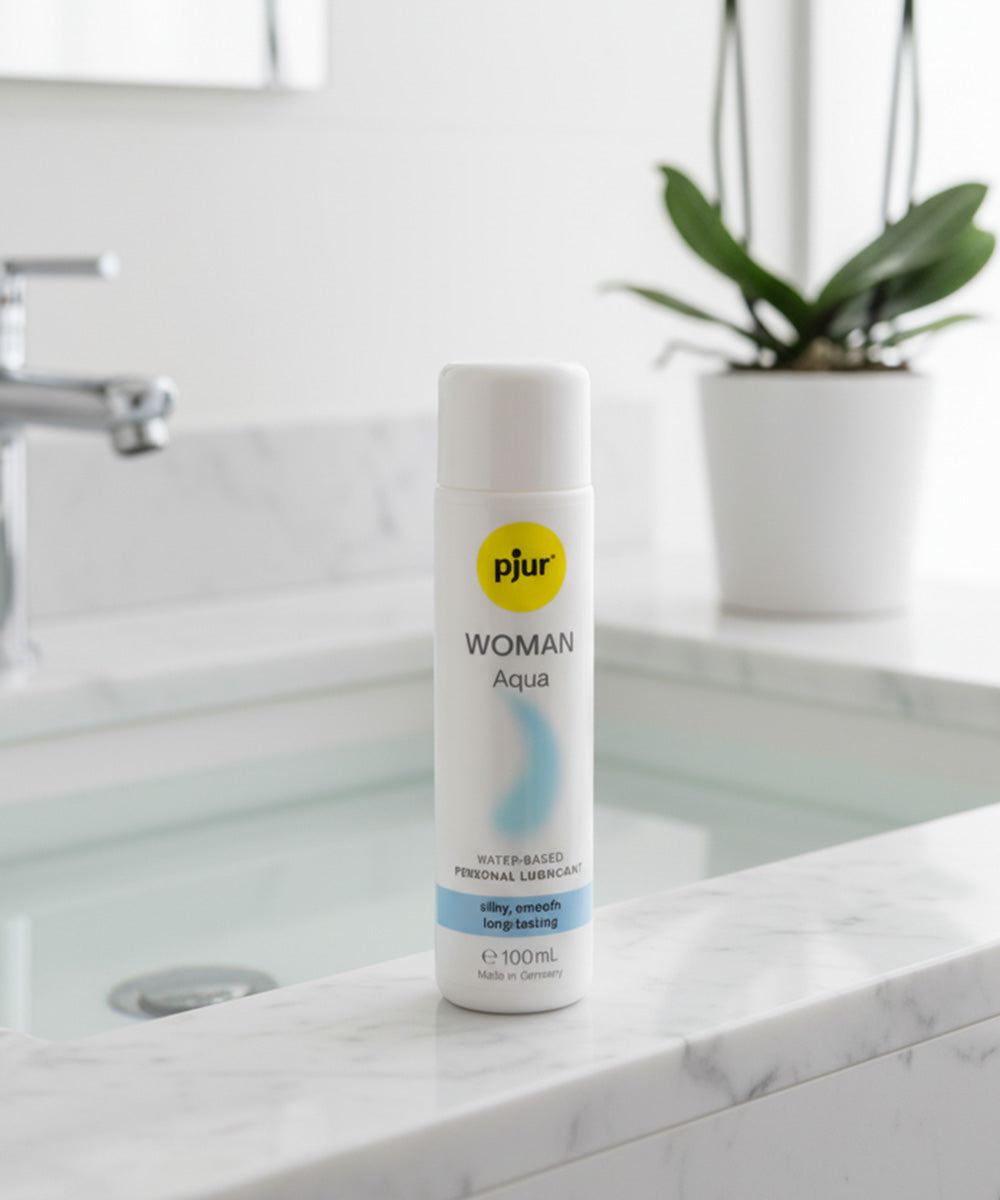 Pjur Woman Aqua personal lubricant bottle on a bathroom counter with a plant in the background