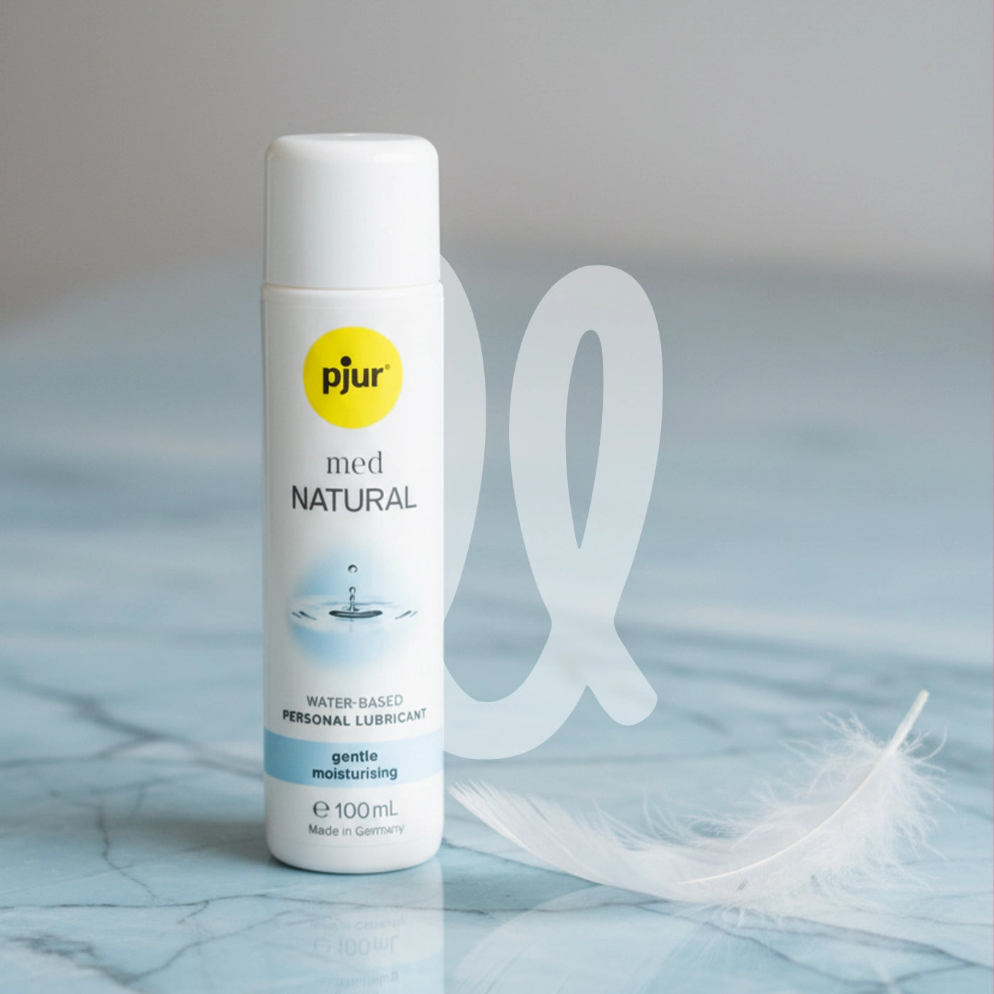 Bottle of Pjur Med Natural lubricant for sensitive skin on a light blue background with a feather.